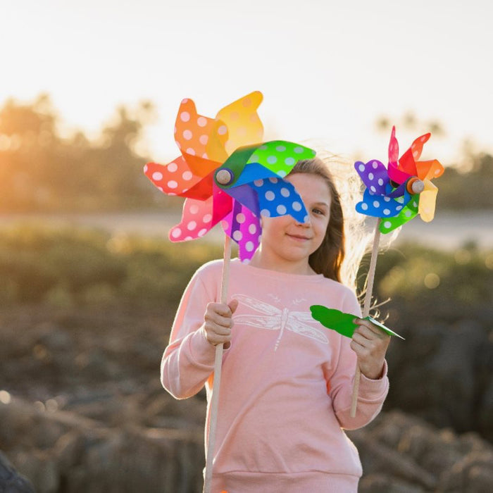 Child holding colorful pinwheels in a natural setting with a blurred background