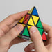 Person solving a Rubik's Pyramid puzzle with a plain background