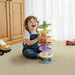 Child playing with a colorful toy on the floor in a room with wooden cabinets and toys.