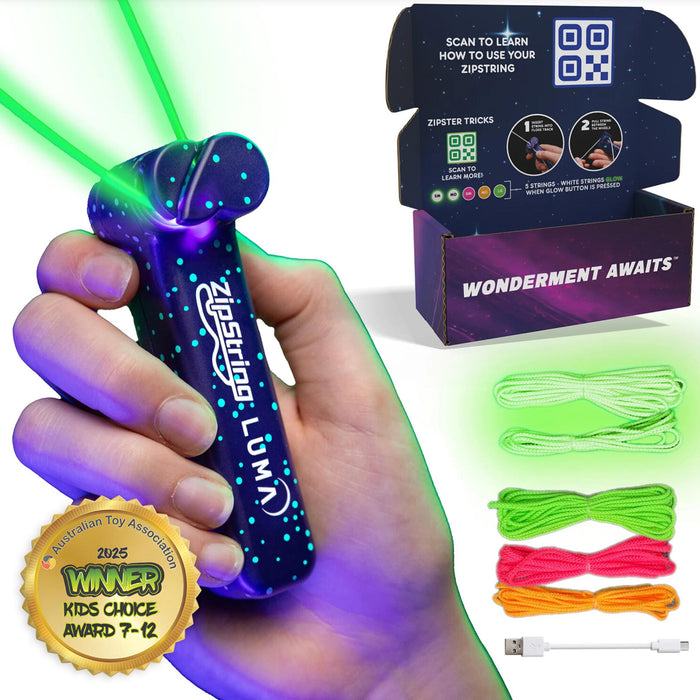A hand holding a purple LED laser pointer toy labeled 'Zipstring Lumi' with green laser beams shooting out, alongside its retail box, three colored zipstring cords, and a USB charging cable on a white background.