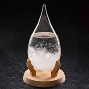 A teardrop-shaped storm glass with visible crystals inside, sitting on a wooden stand.