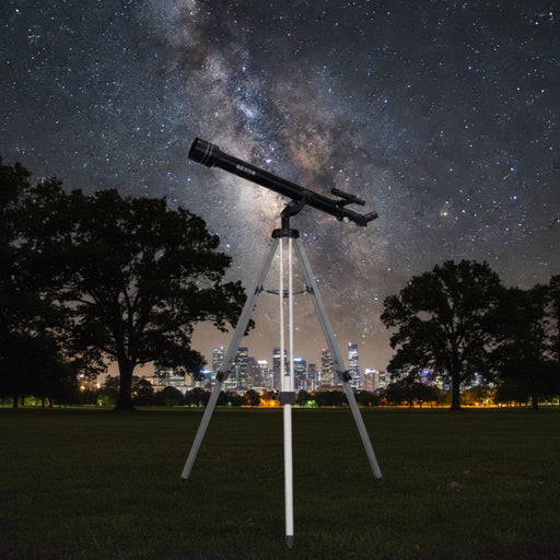 Telescope on a tripod against a starry night sky with city lights in the background